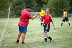 A soccer coach congratulates a player